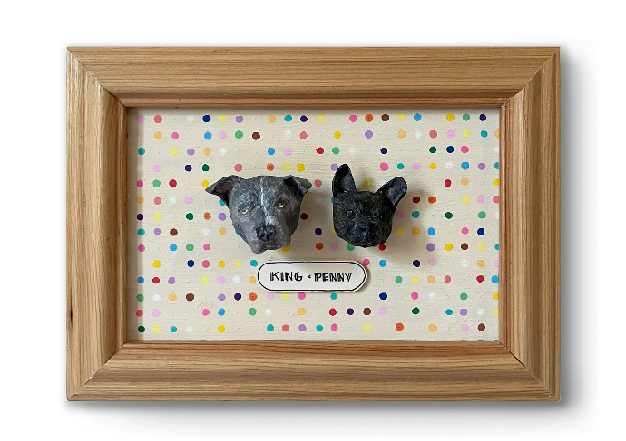 Handmade papier-mâché portraits of two dogs, King and Penny, in a wooden frame
